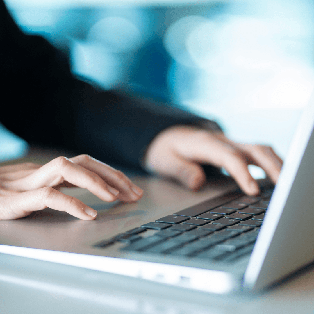 A person's hands typing on a laptop keyboard.